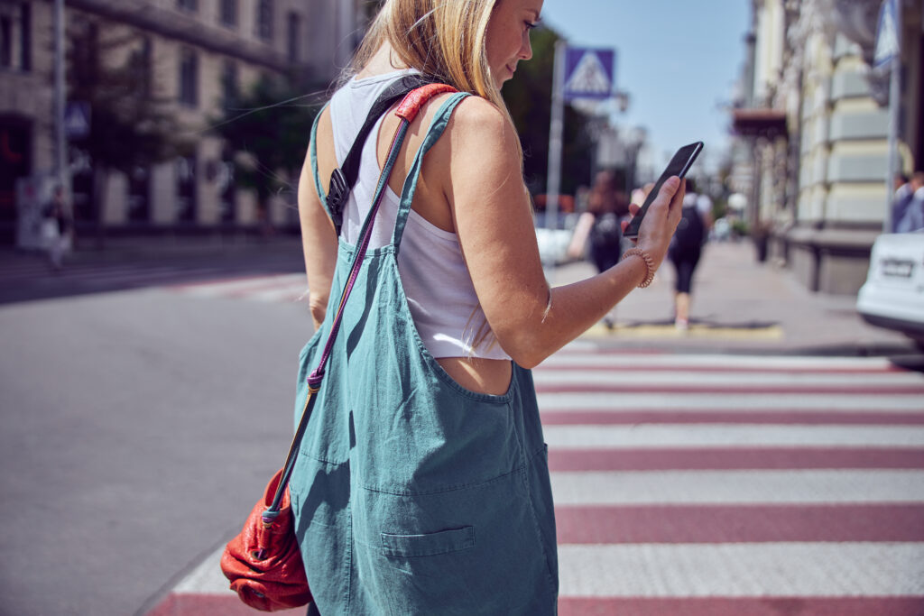 cheerful lady with smartphone on the crosswalk 2021 09 03 17 25 39 utc